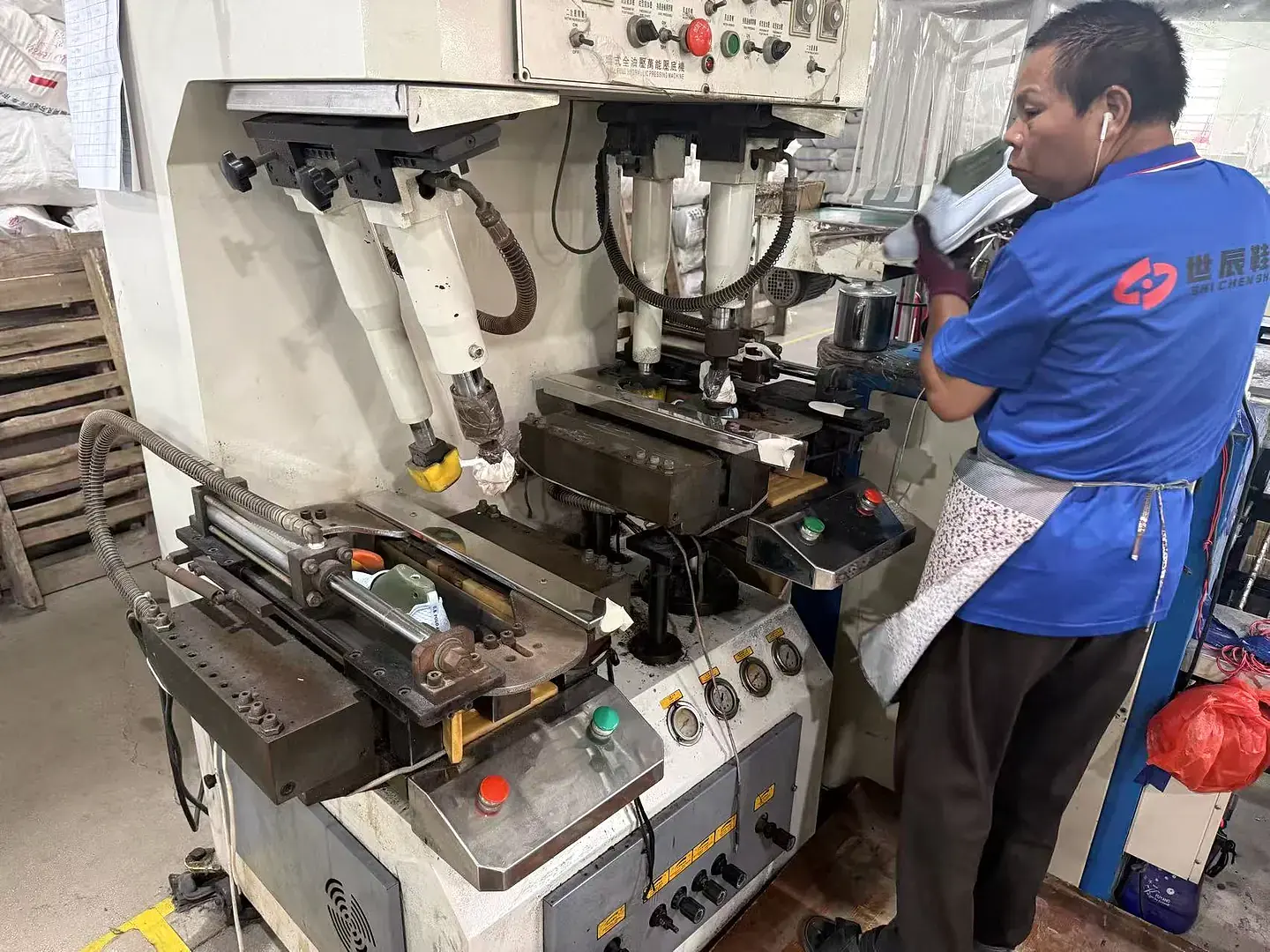 Footwear production employee working at a hydraulic press workstation