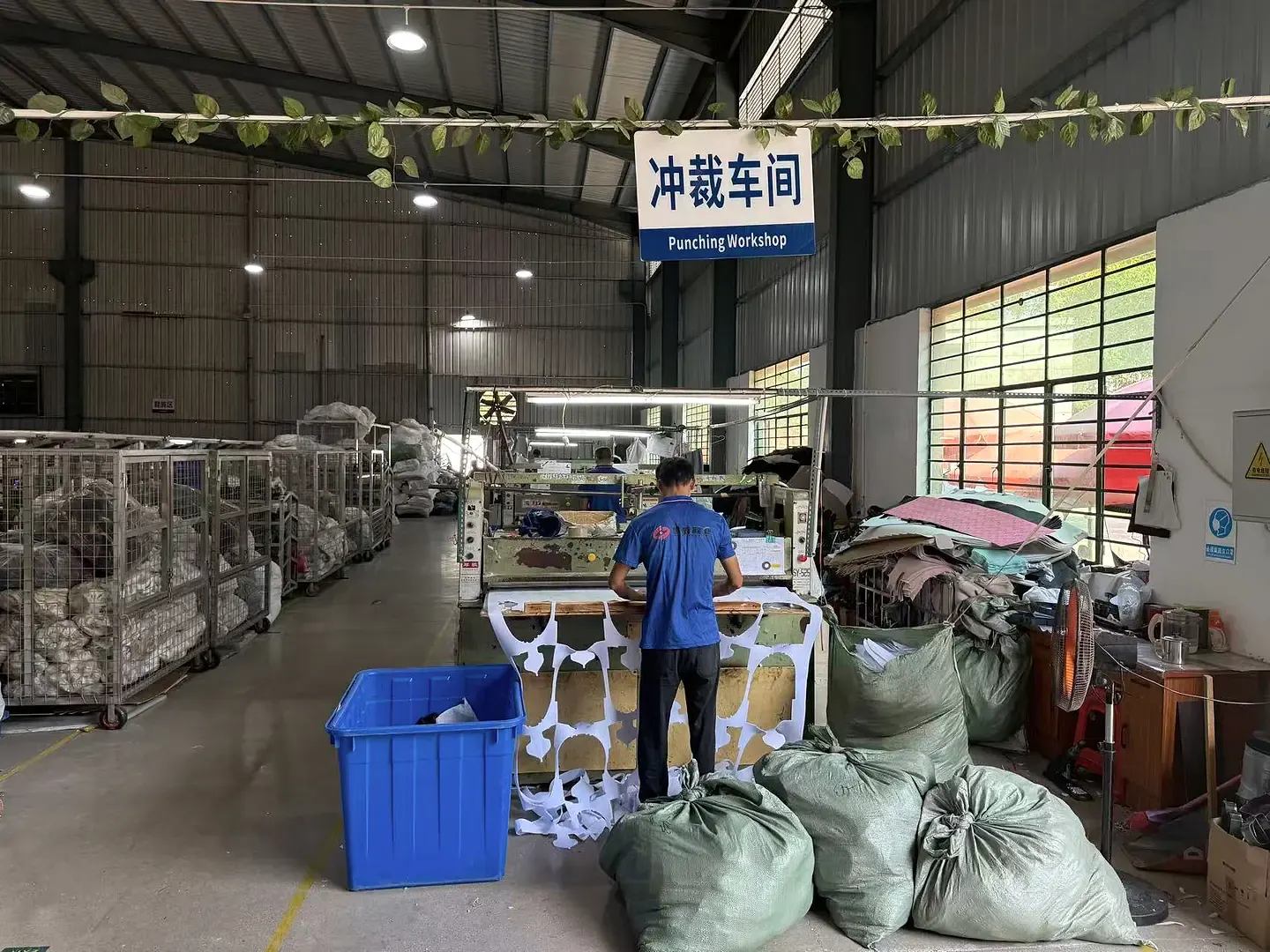 Wide view of employees working with footwear material-cutting equipment