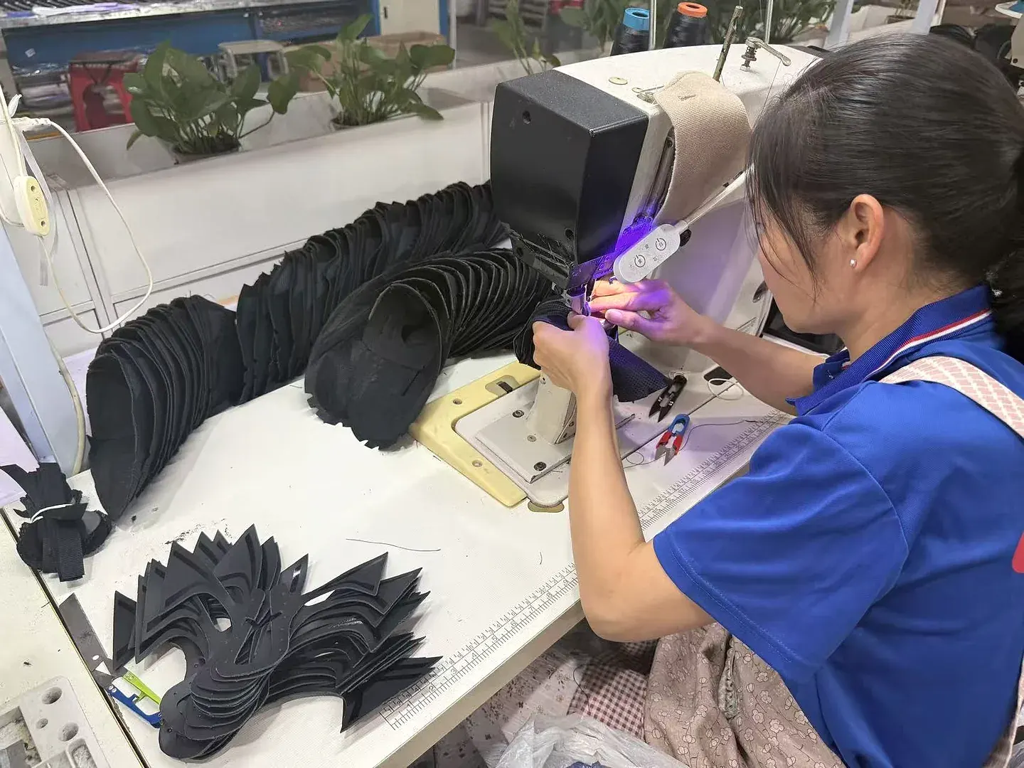 GRAND STAR employee stitching footwear upper components at an industrial sewing machine